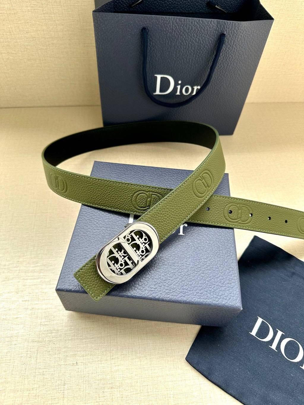 Green leather belt with silver-toned oval buckle and embossed oval motif