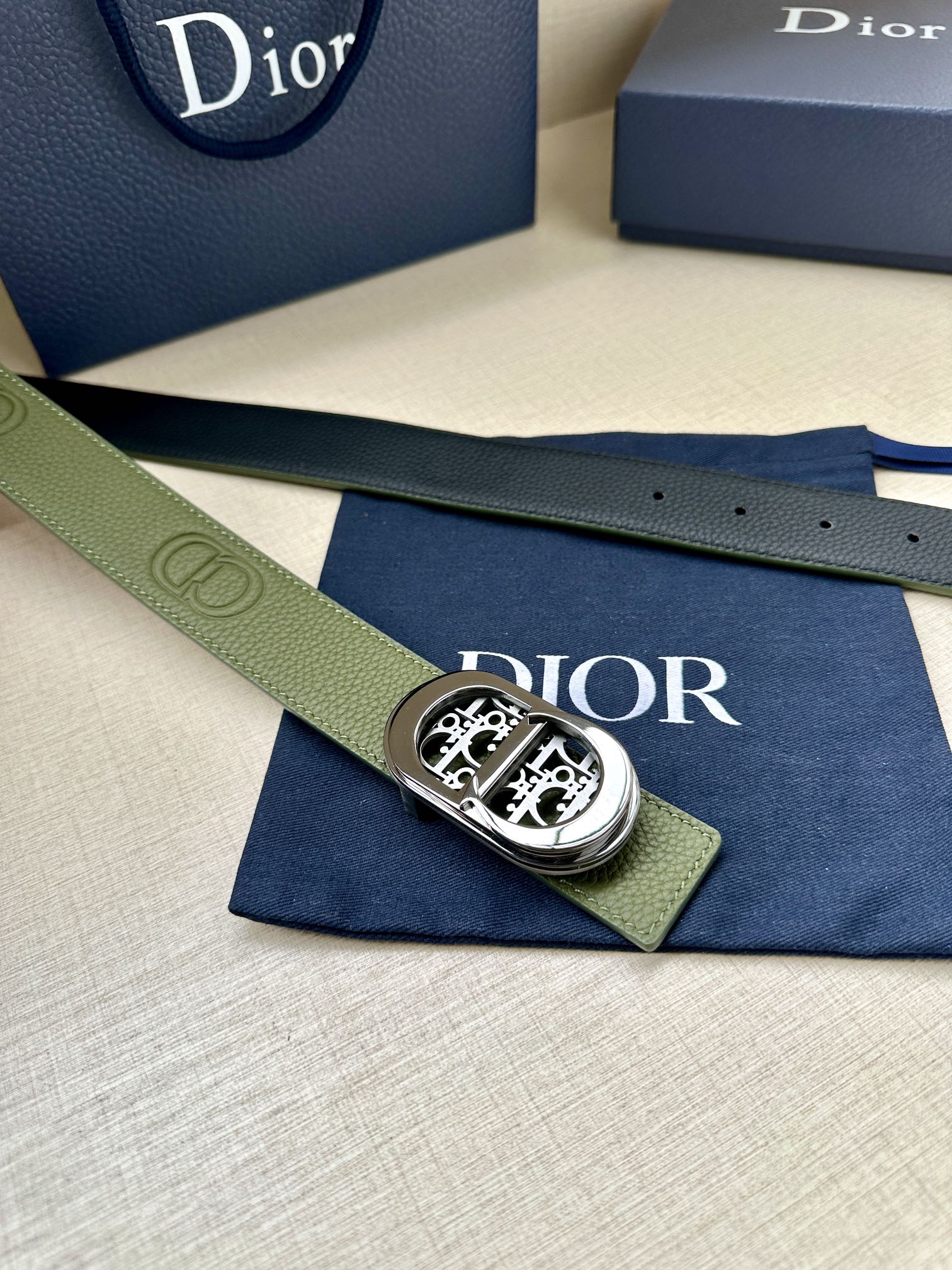 Green leather belt with silver-toned oval buckle and embossed logo segment