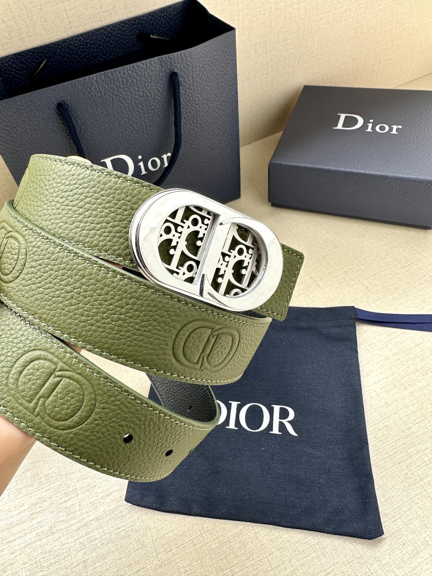 Green leather belt with silver-toned oval buckle and embossed logo panel
