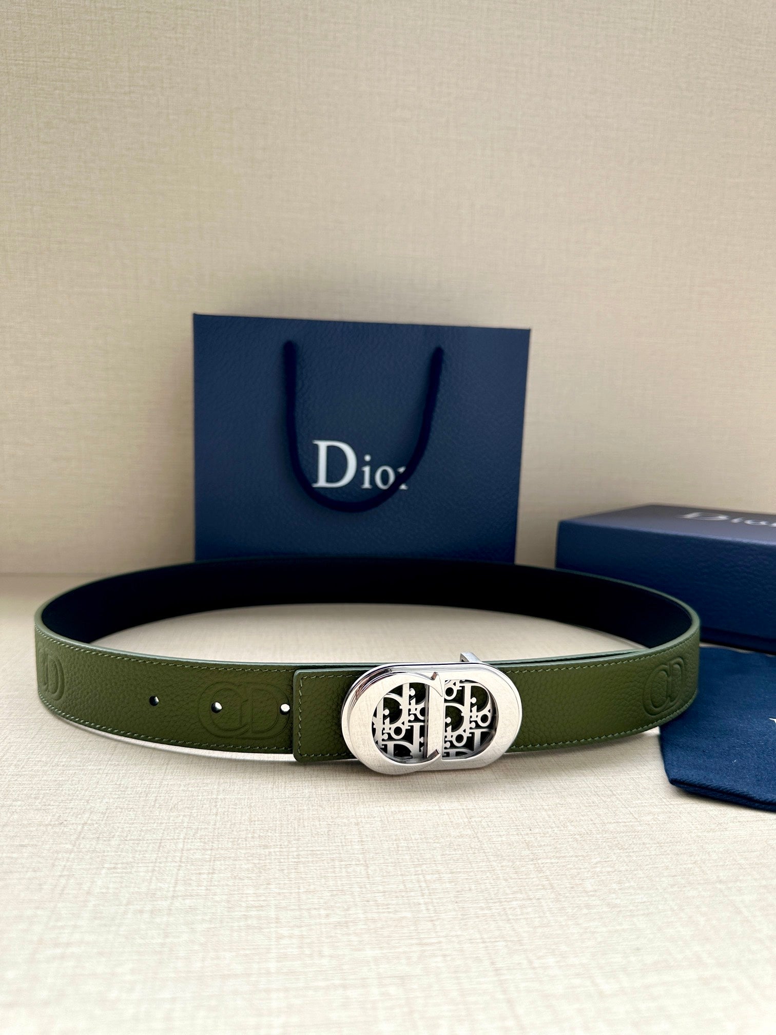Green leather belt with silver-toned oval logo buckle and stitched holes