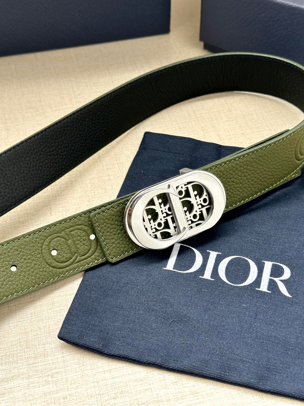 Green leather belt with silver-toned buckle and embossed circular logo detail