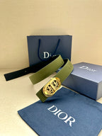 Green leather belt with gold-toned oval logo buckle and embossed monogram