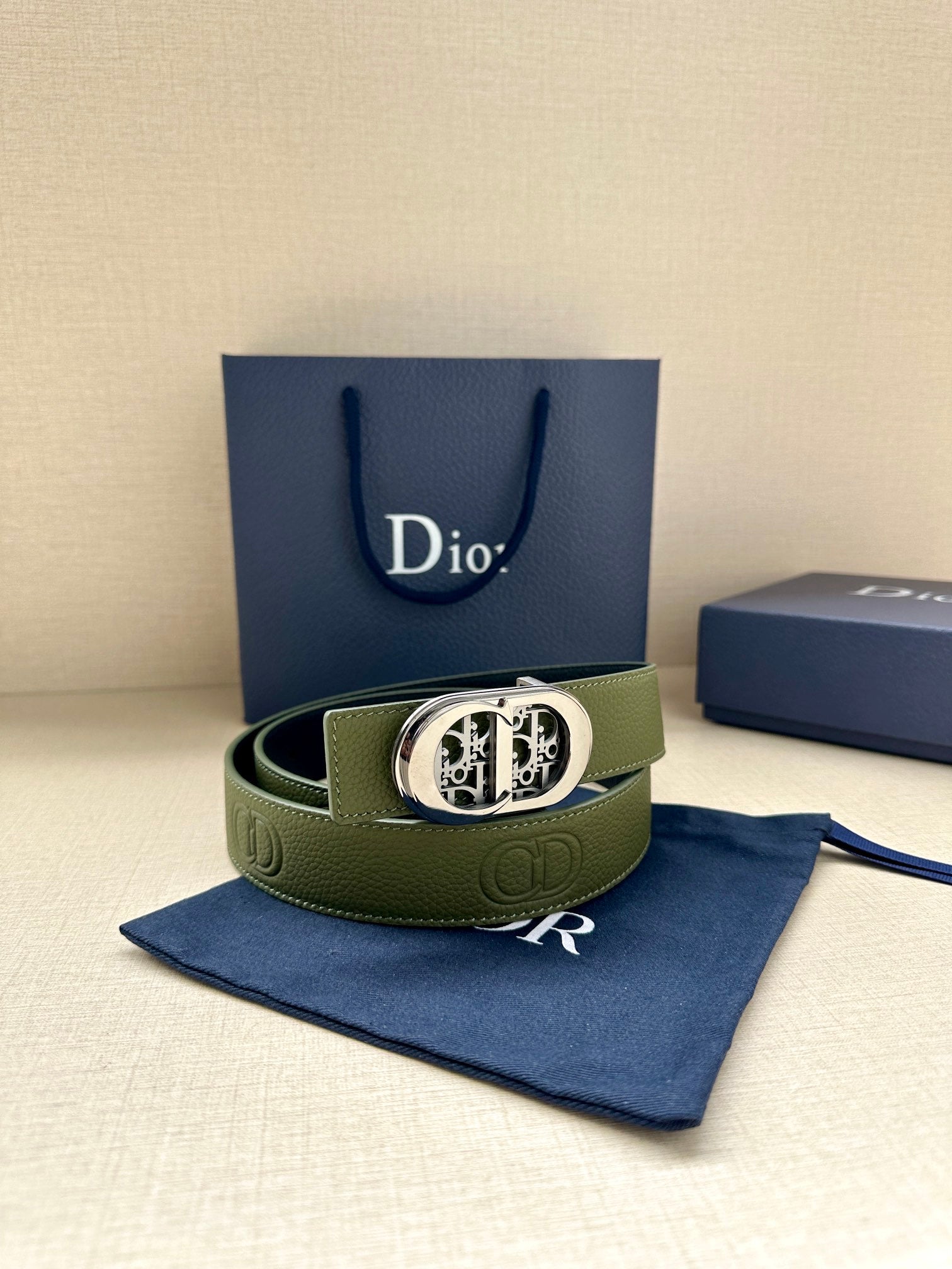 Green leather belt with silver-toned oval logo buckle and textured leather finish