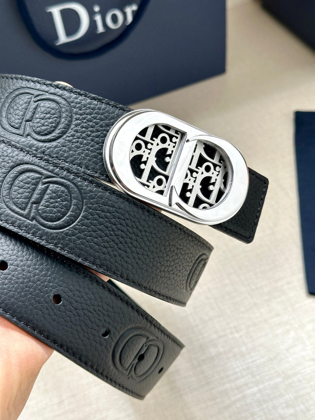 Dior belt close-up: black leather strap with silver-tone oval monogram buckle