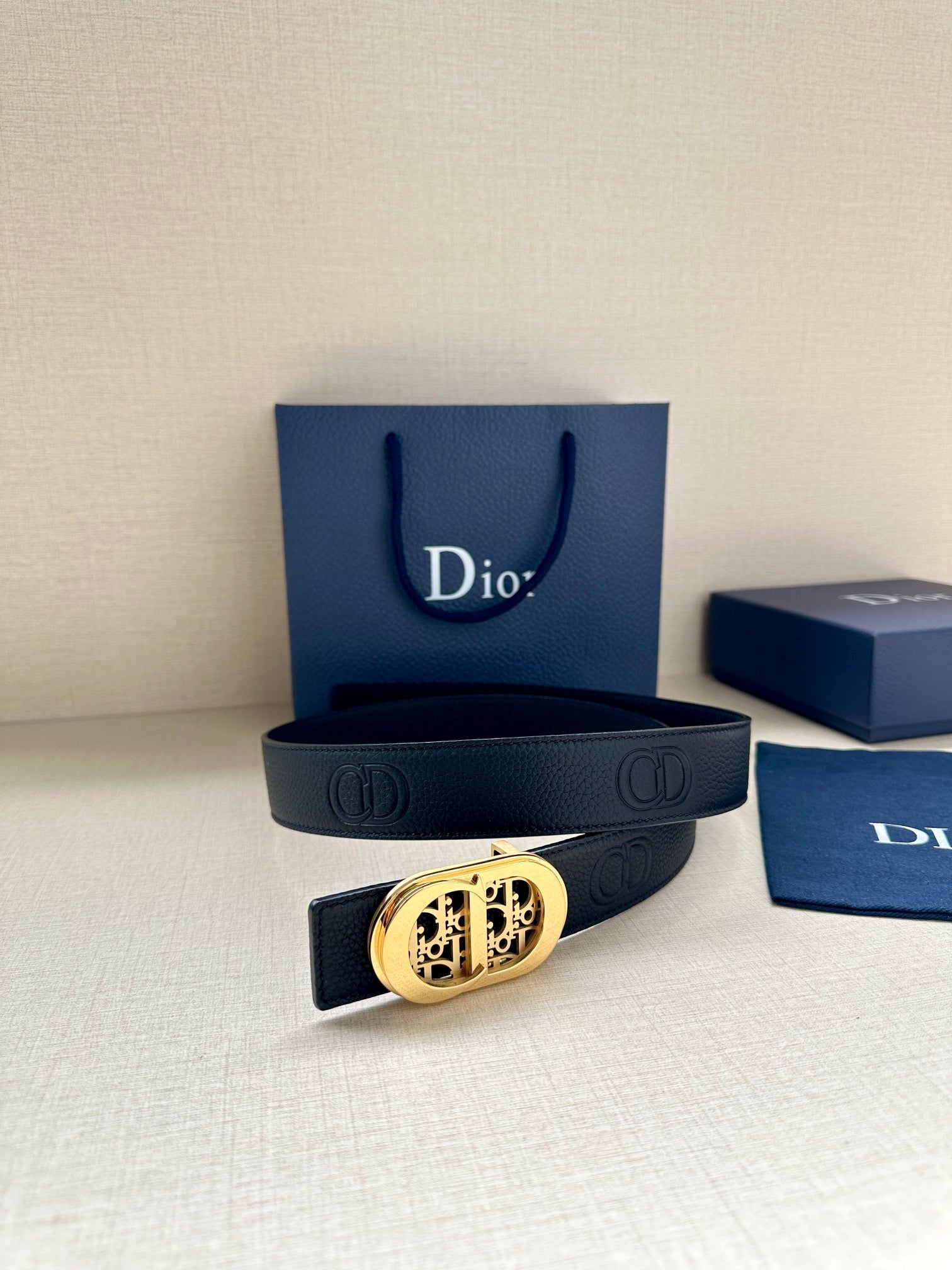 Dior belt featuring dark leather with oval logo buckle and double-ring strap ends