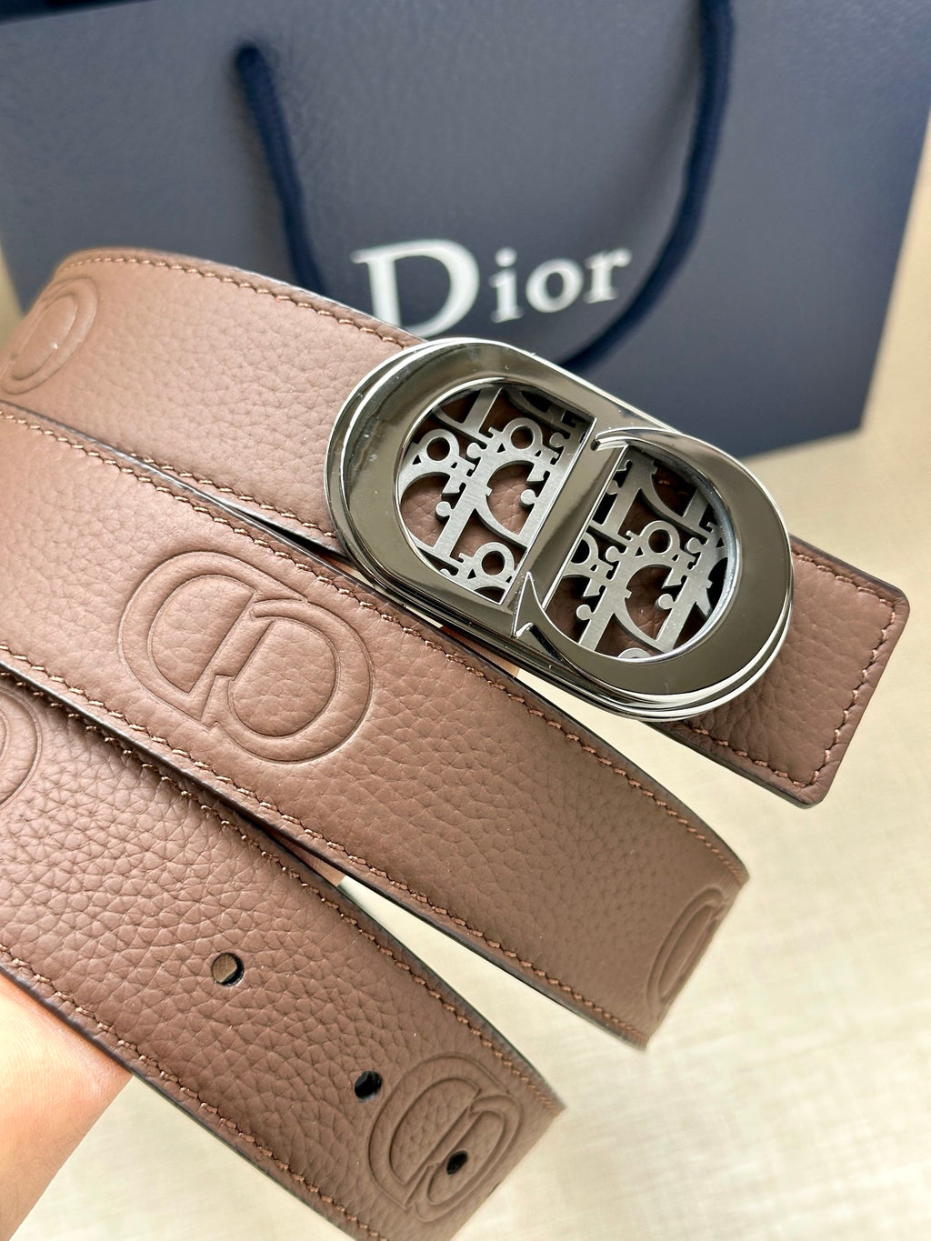 Dior leather belt close-up: tan-brown strap with logo and silver buckle