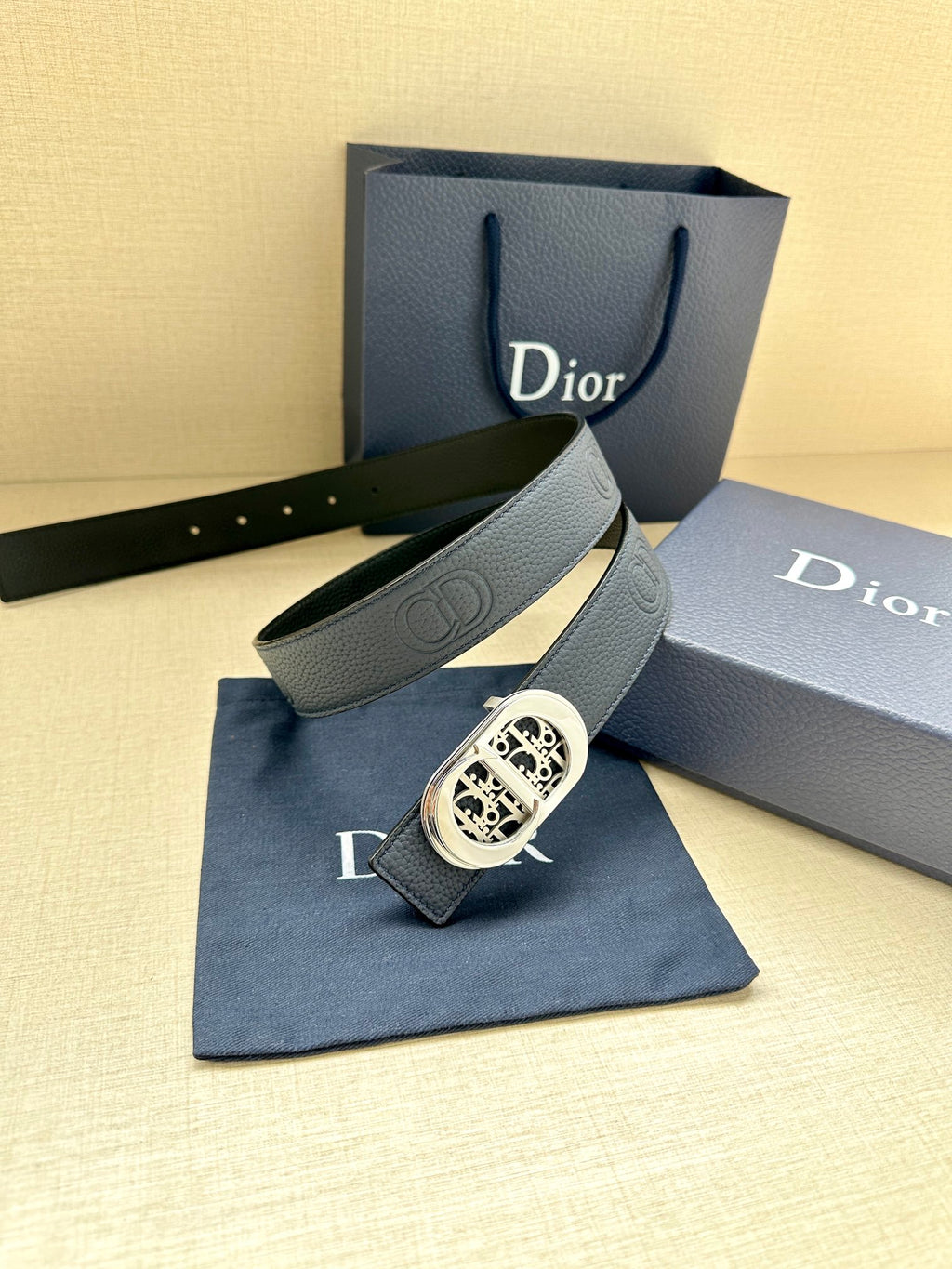 Dior leather belt with light gray-blue strap texture and silver-toned logo buckle
