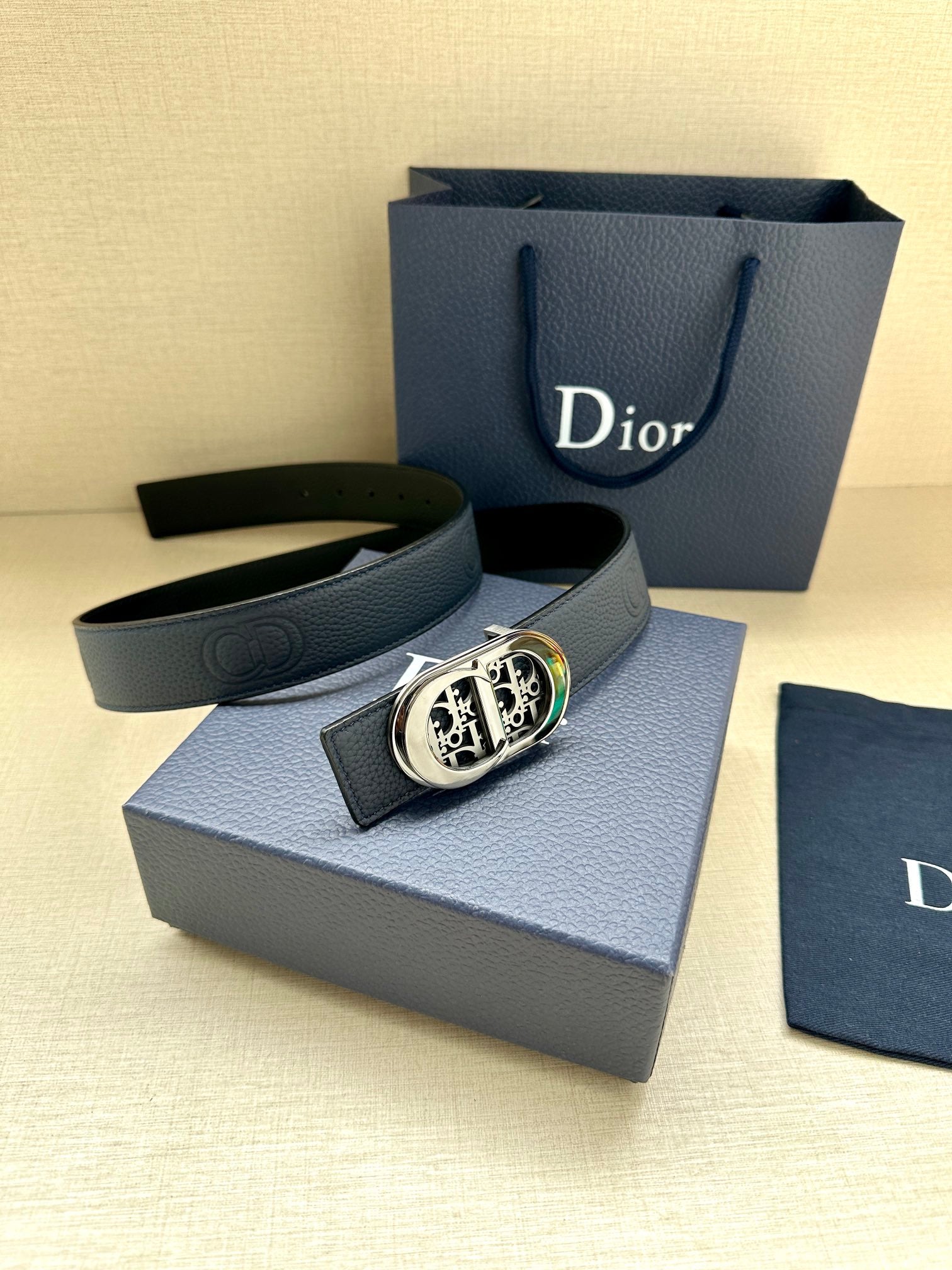 Dior leather belt with dark blue strap and round gold-and-silver logo buckle