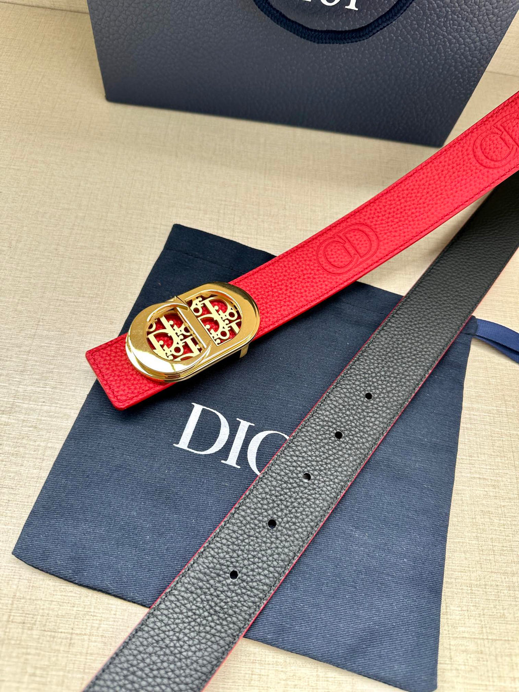 Red leather belt with gold-tone logo buckle, on blue dust bag