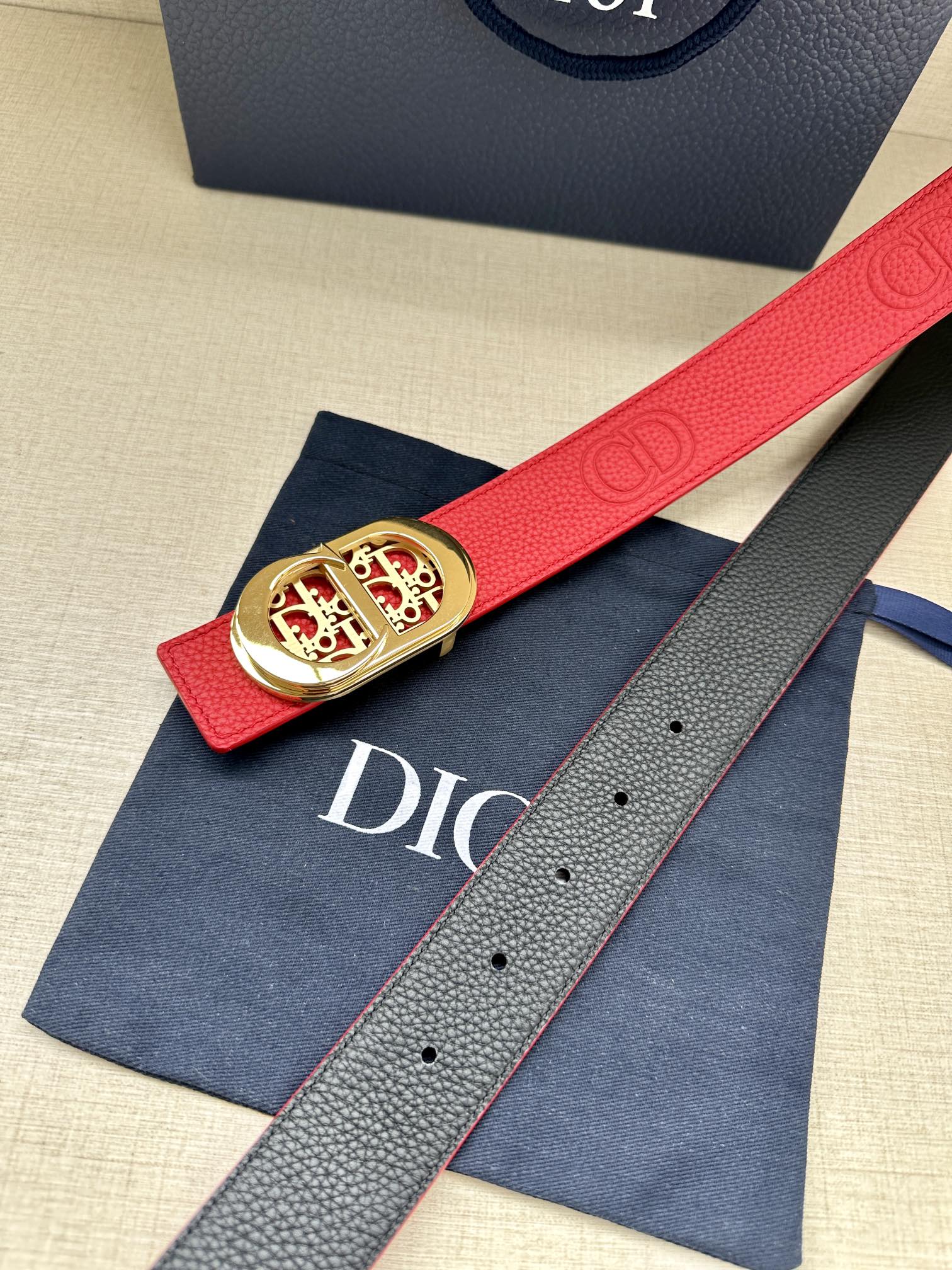 Red leather belt with gold-tone logo buckle, on blue dust bag
