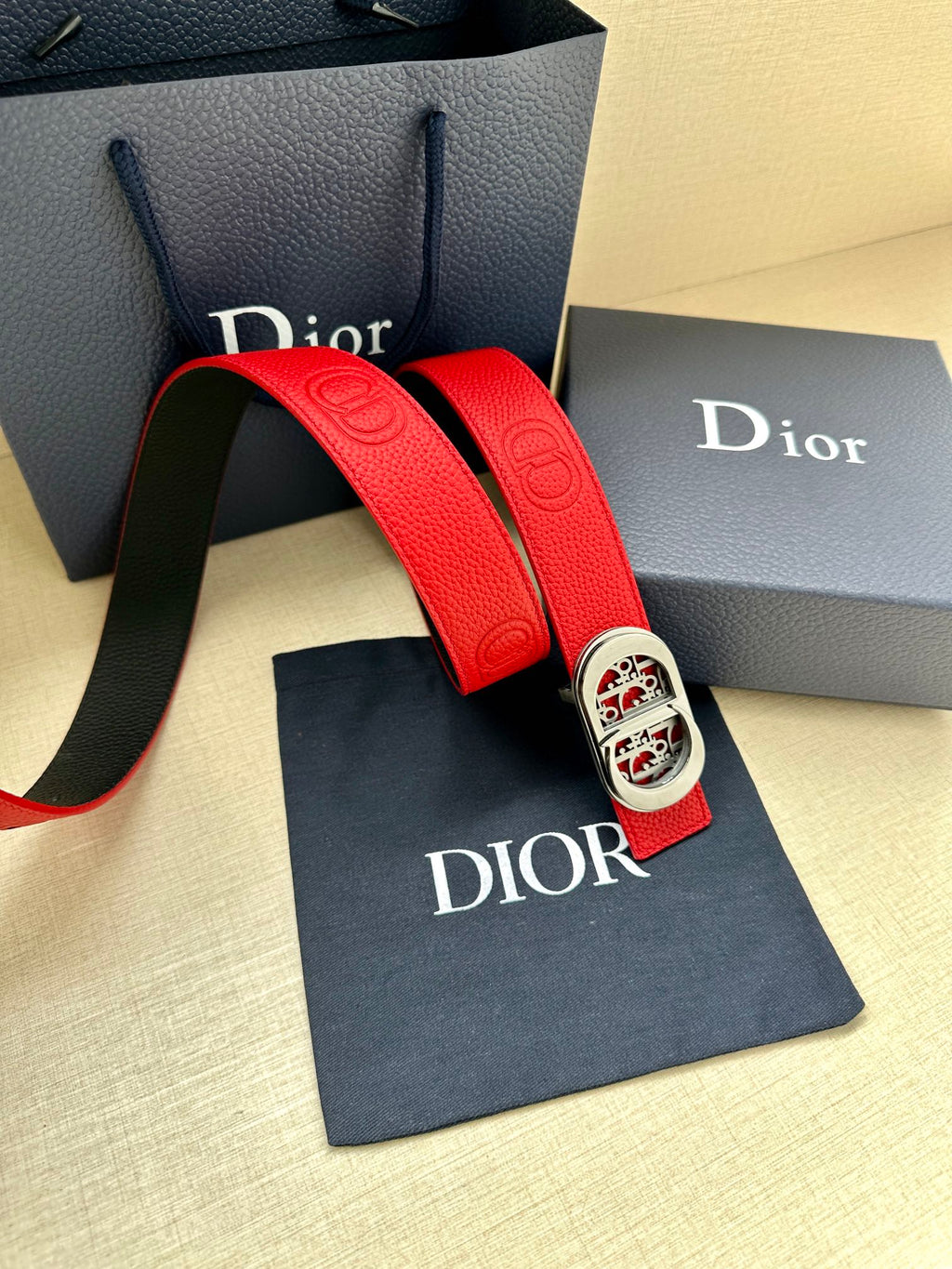 Red leather belt with silver-tone oval logo buckle and textured end tab