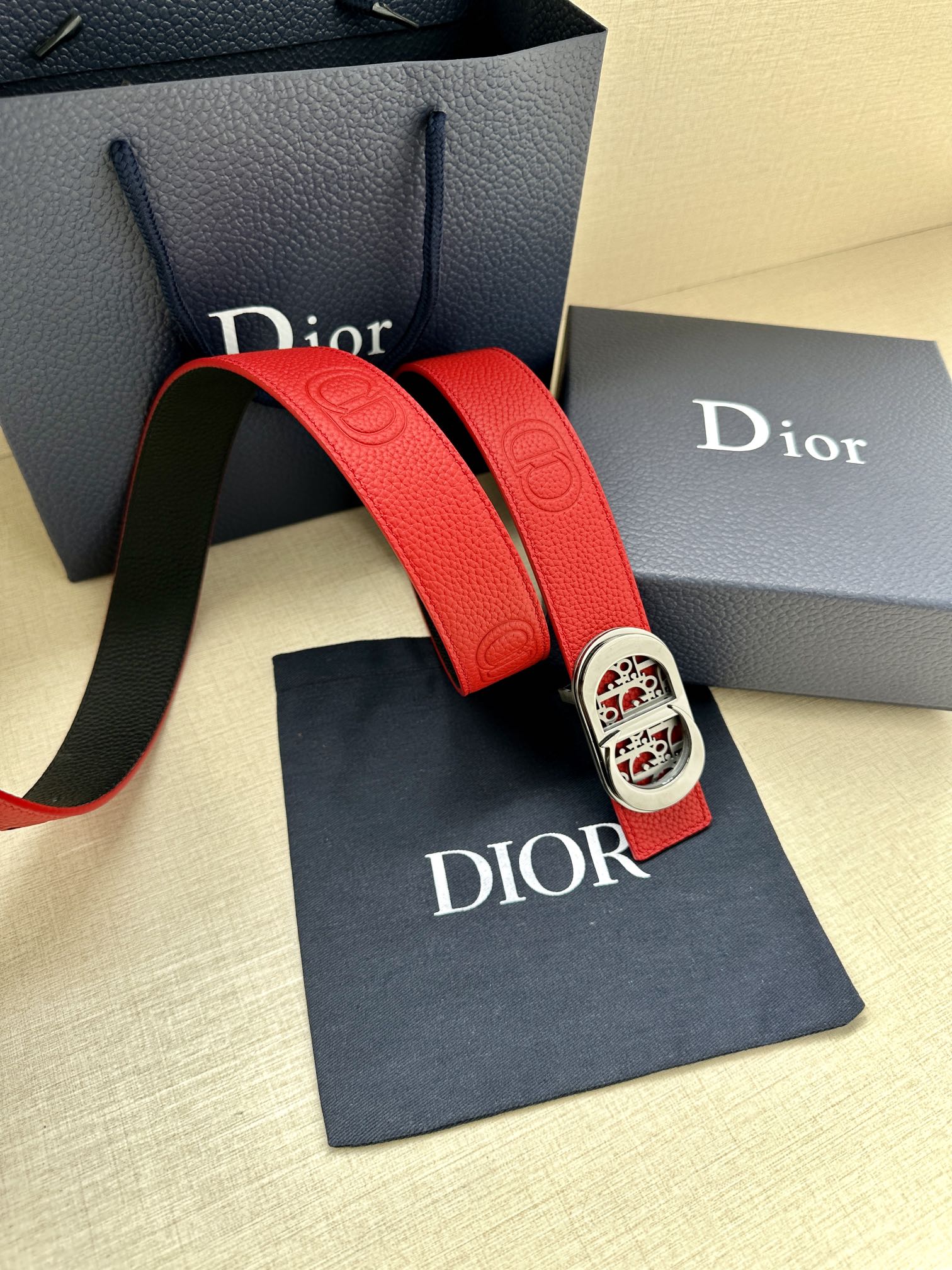 Red leather belt with silver-tone oval logo buckle and textured end tab