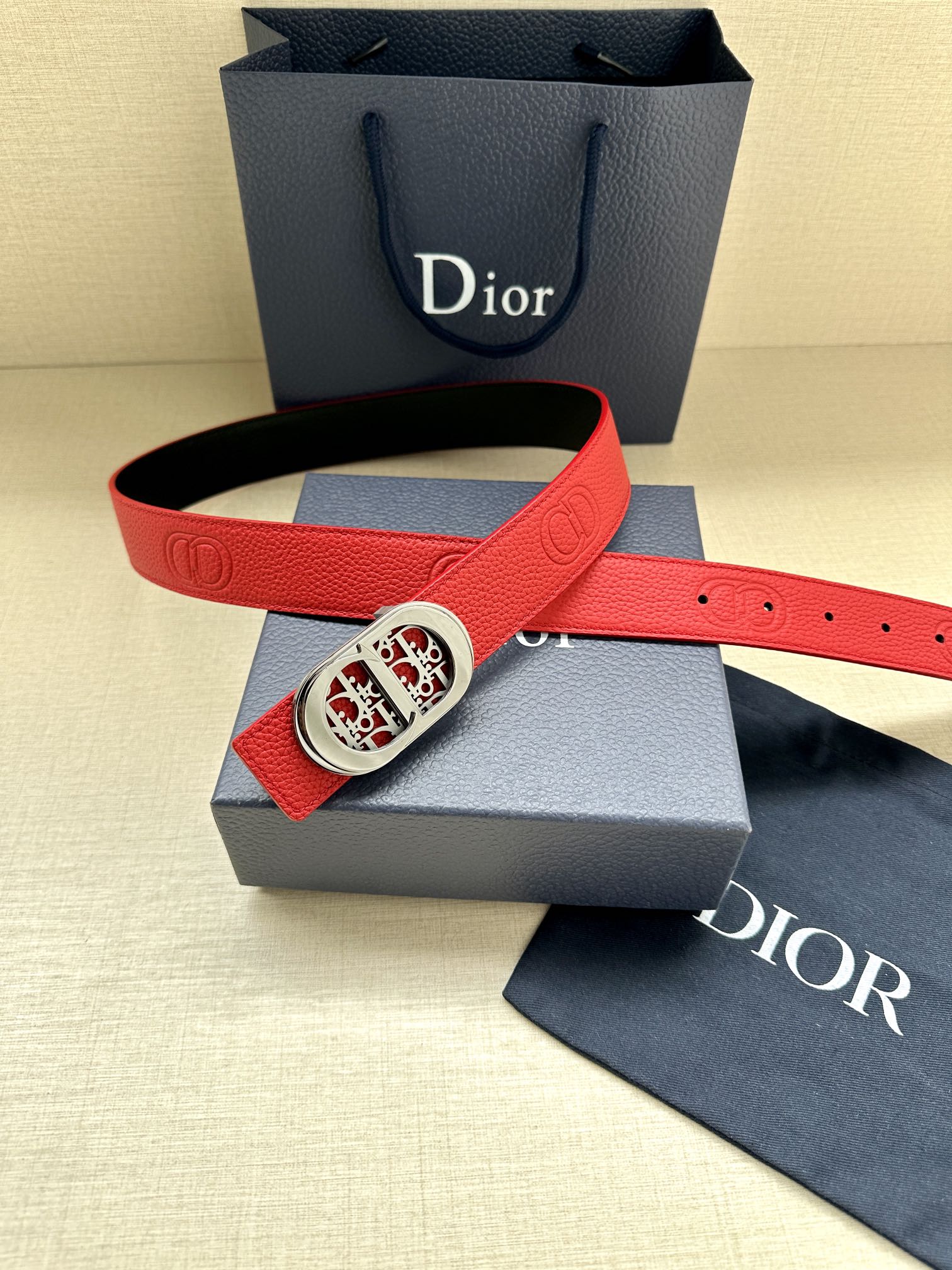 Red leather belt with silver-tone oval logo buckle, shown with gift box