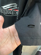 Black short-sleeve T-shirt fabric close-up with white logo print and stitched hem