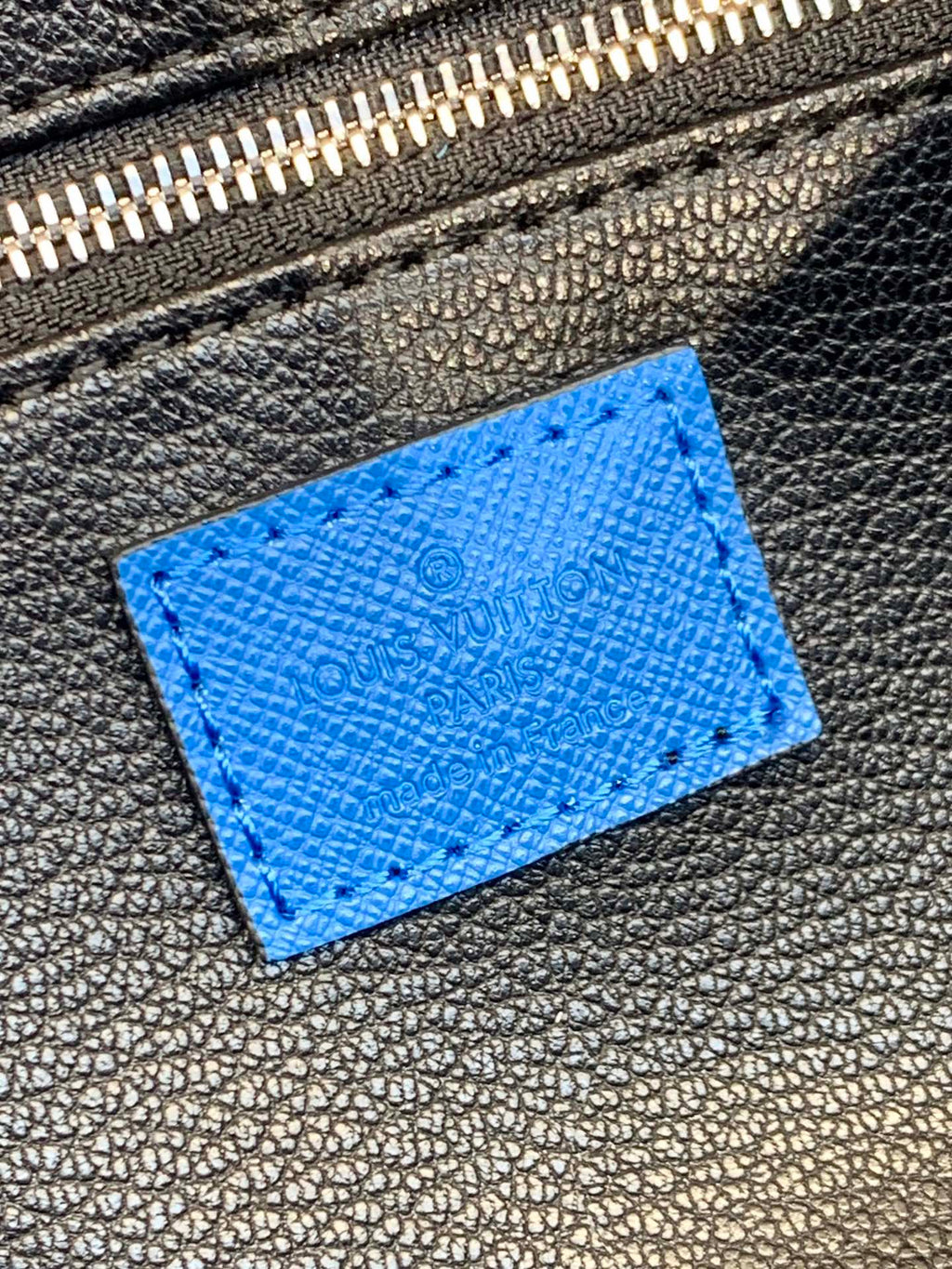 Louis Vuitton blue monogram leather patch detail on dark zipper