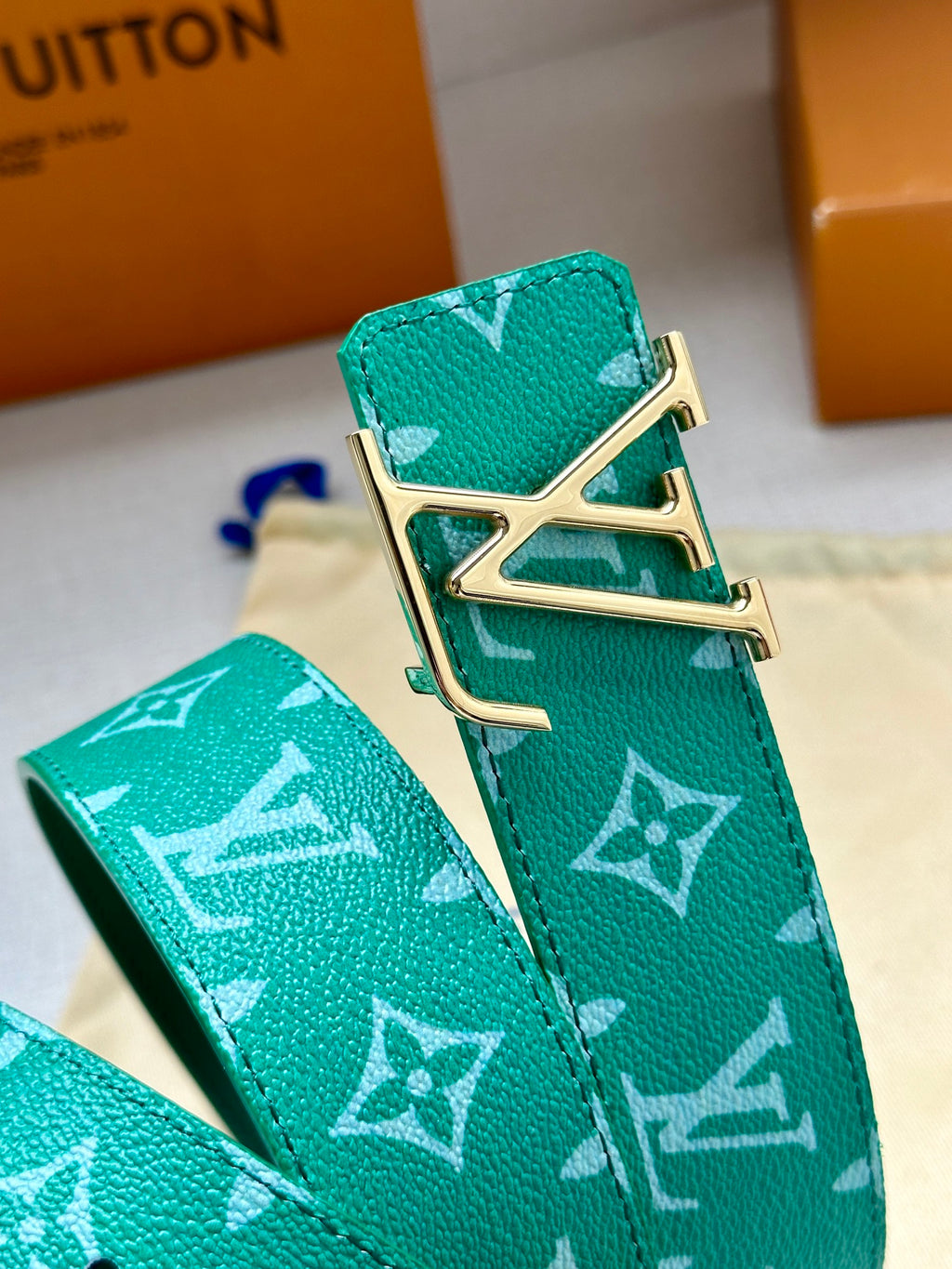 Louis Vuitton green monogram belt buckle close-up with gold-tone hardware