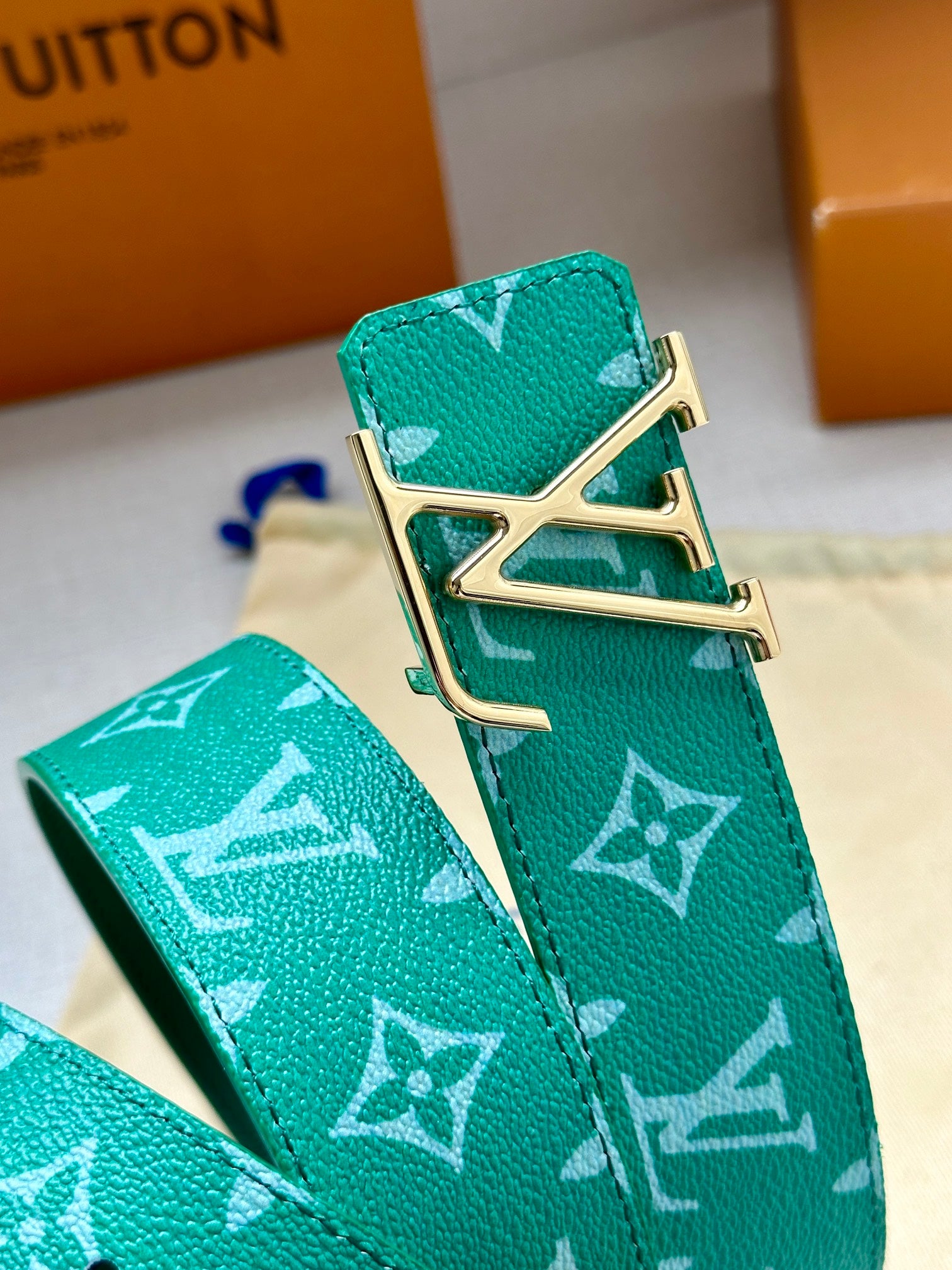 Louis Vuitton green monogram belt buckle close-up with gold-tone hardware