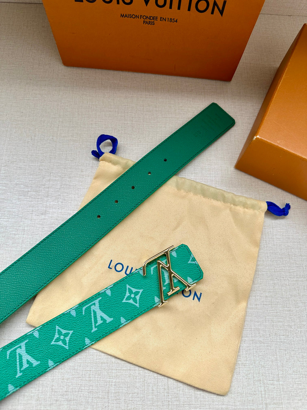Louis Vuitton green monogram belt laid flat with gold-tone LV buckle