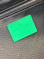 Green leather label patch on black textured bag with silver-tone zipper teeth