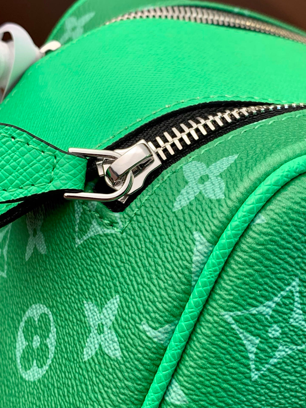 Louis Vuitton monogram bag zipper close-up on bright green pebbled leather