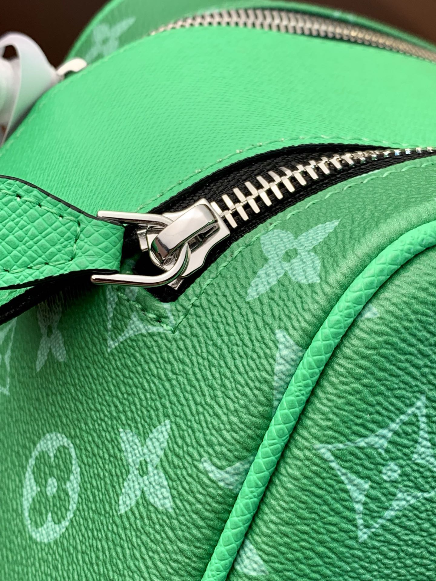Louis Vuitton monogram bag zipper close-up on bright green pebbled leather