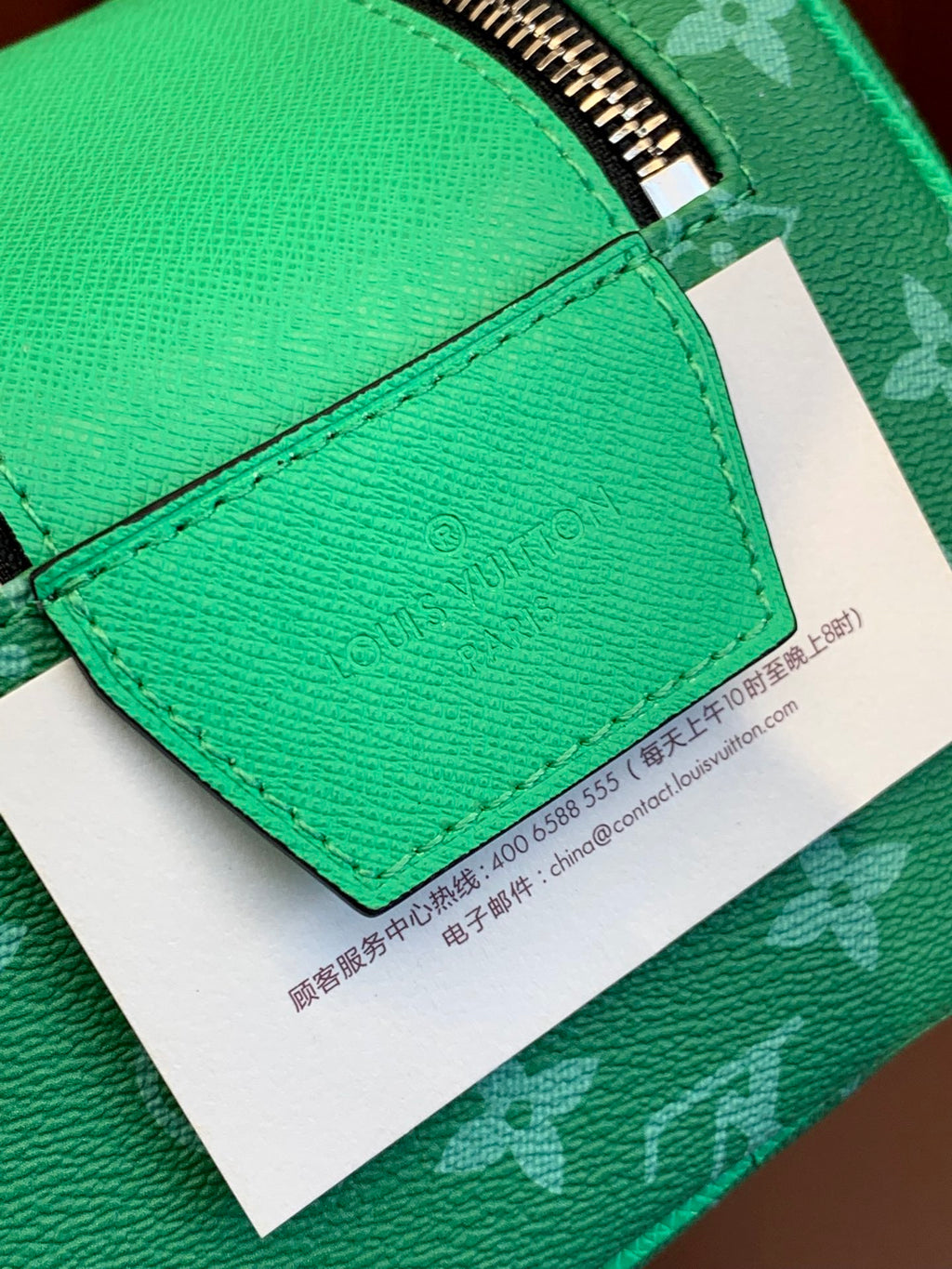 Green leather flap with printed care tag on Louis Vuitton monogram bag