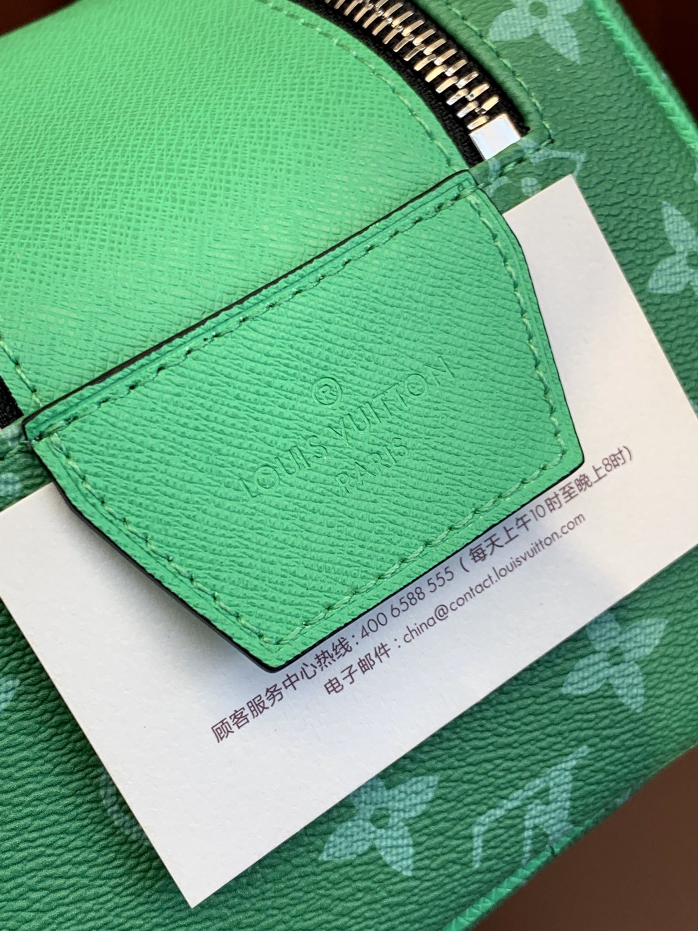 Green leather flap with printed care tag on Louis Vuitton monogram bag