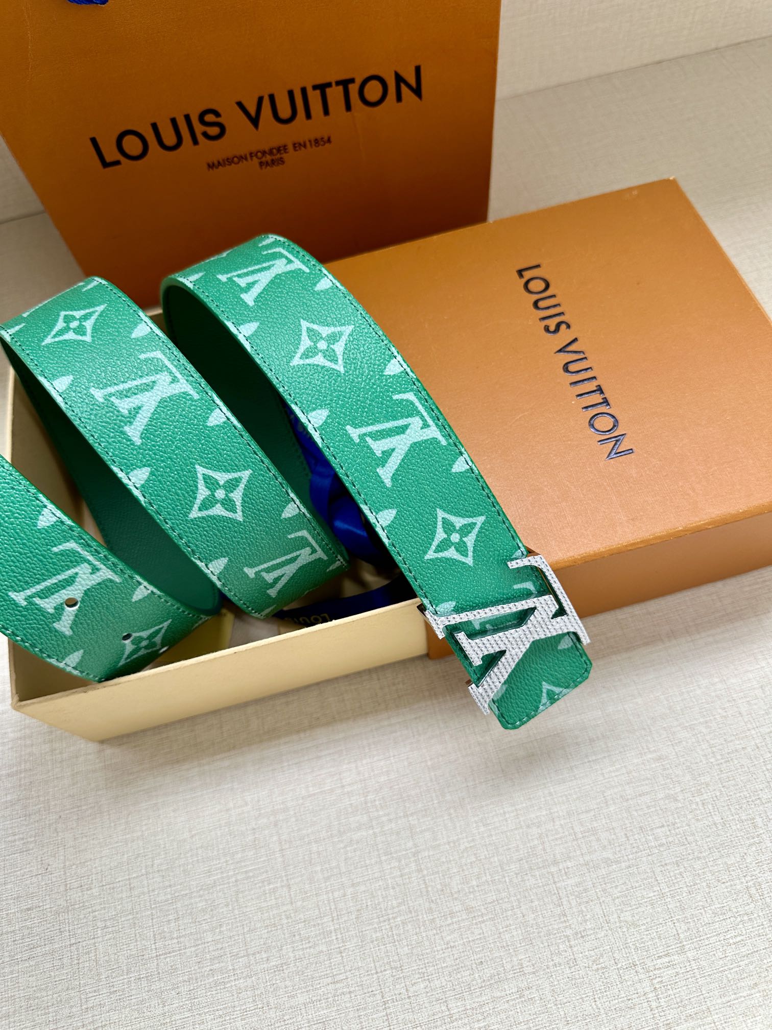 Green logo belt with gold buckle, shown folded with matching strap loops