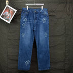 Blue denim pants with light cross embroidery on legs; button fly and belt loops.