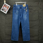 Blue denim pants with cross embroidery on back; rear pockets and small yellow label.