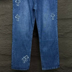 Blue denim pants with cross embroidery on both legs and straight cropped hem.