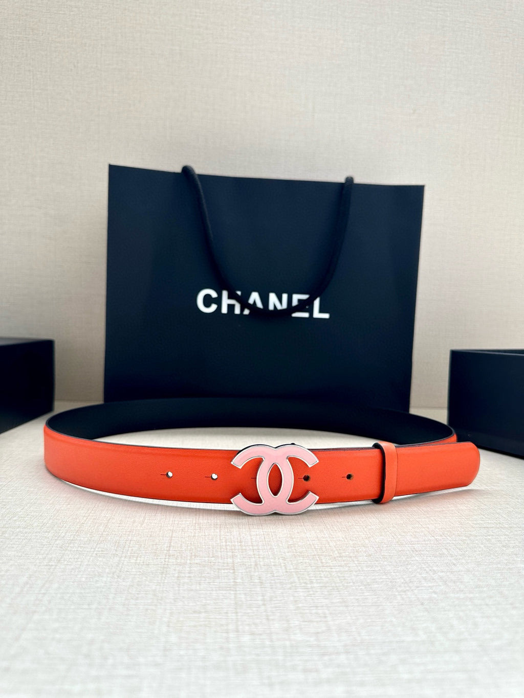 Chanel belt with bright orange leather strap and white CC buckle, shown laid flat