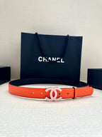 Chanel belt with bright orange leather strap and white CC buckle, shown laid flat