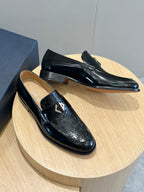 Dior unisex patent leather loafers, black with gold emblem, angled on stand