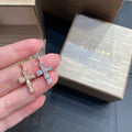 Bvlgari cross earrings in gold tone with clear pavé stones, held in hand