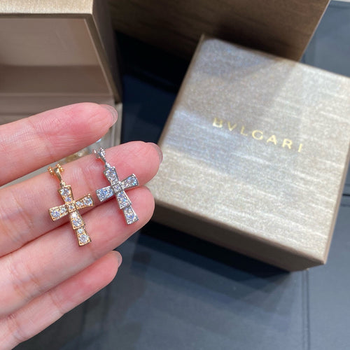 Bvlgari cross earrings in gold tone with clear pavé stones, held in hand