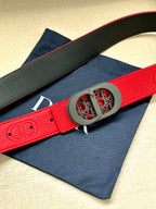 Red leather Dior belt with textured strap and gray oval patterned logo buckle.