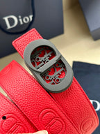 Red textured leather Dior belt with gray oval buckle and embossed strap design.