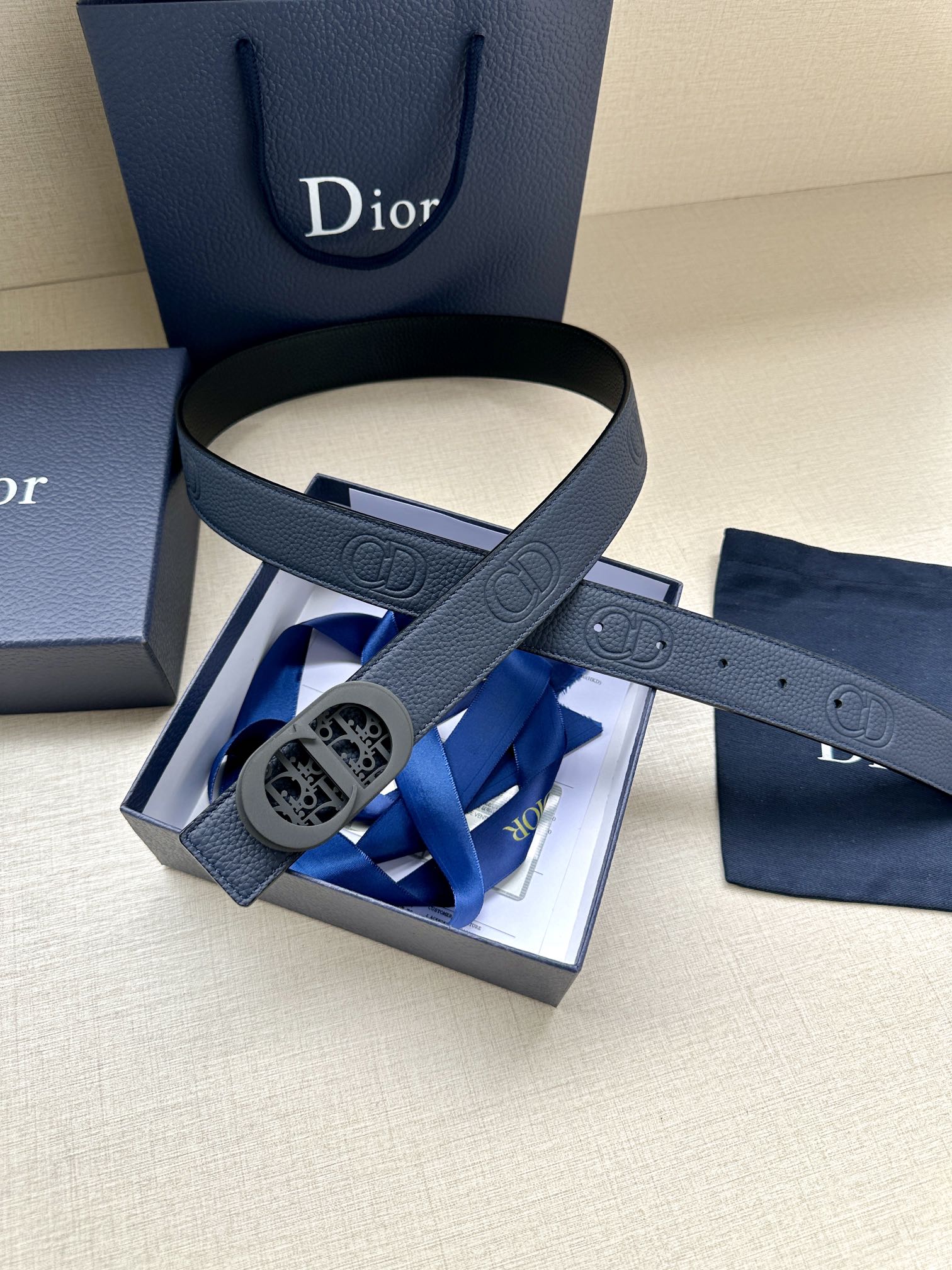 Dior belt with blue leather strap and oval logo buckle, laid flat