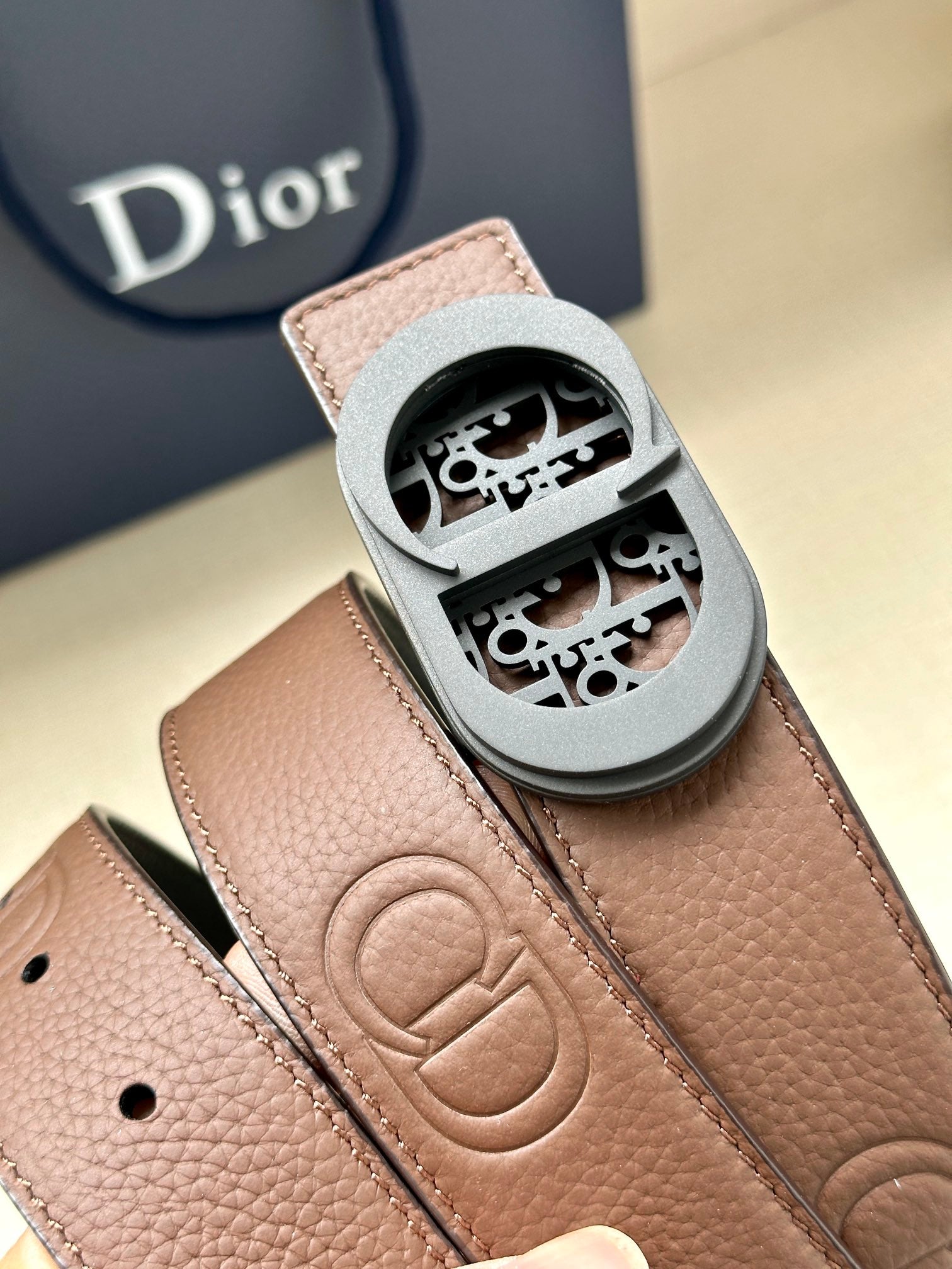 Brown leather belt buckle with engraved Dior monogram and stitched strap