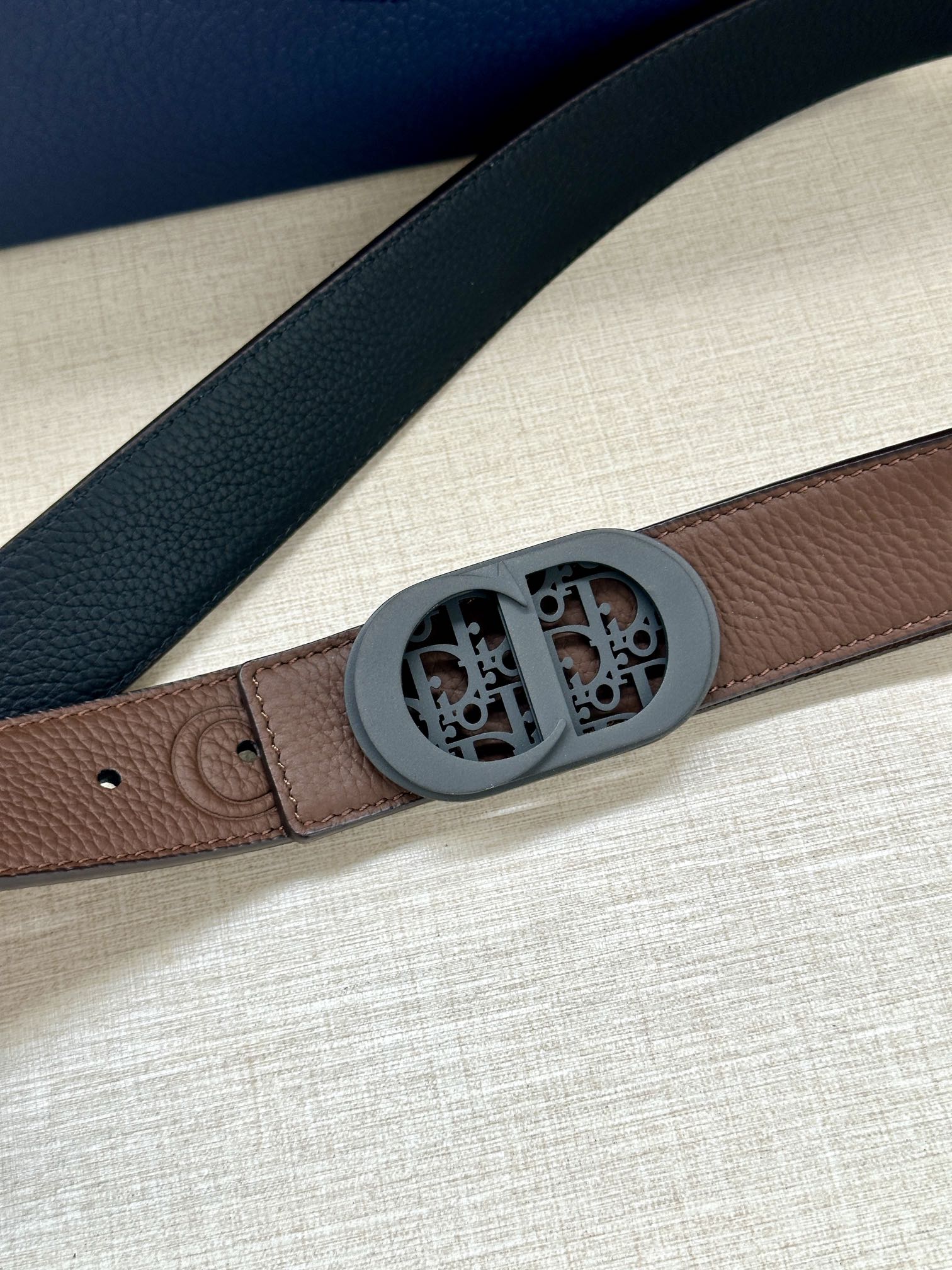 Brown leather belt with textured edge and oval monogram buckle