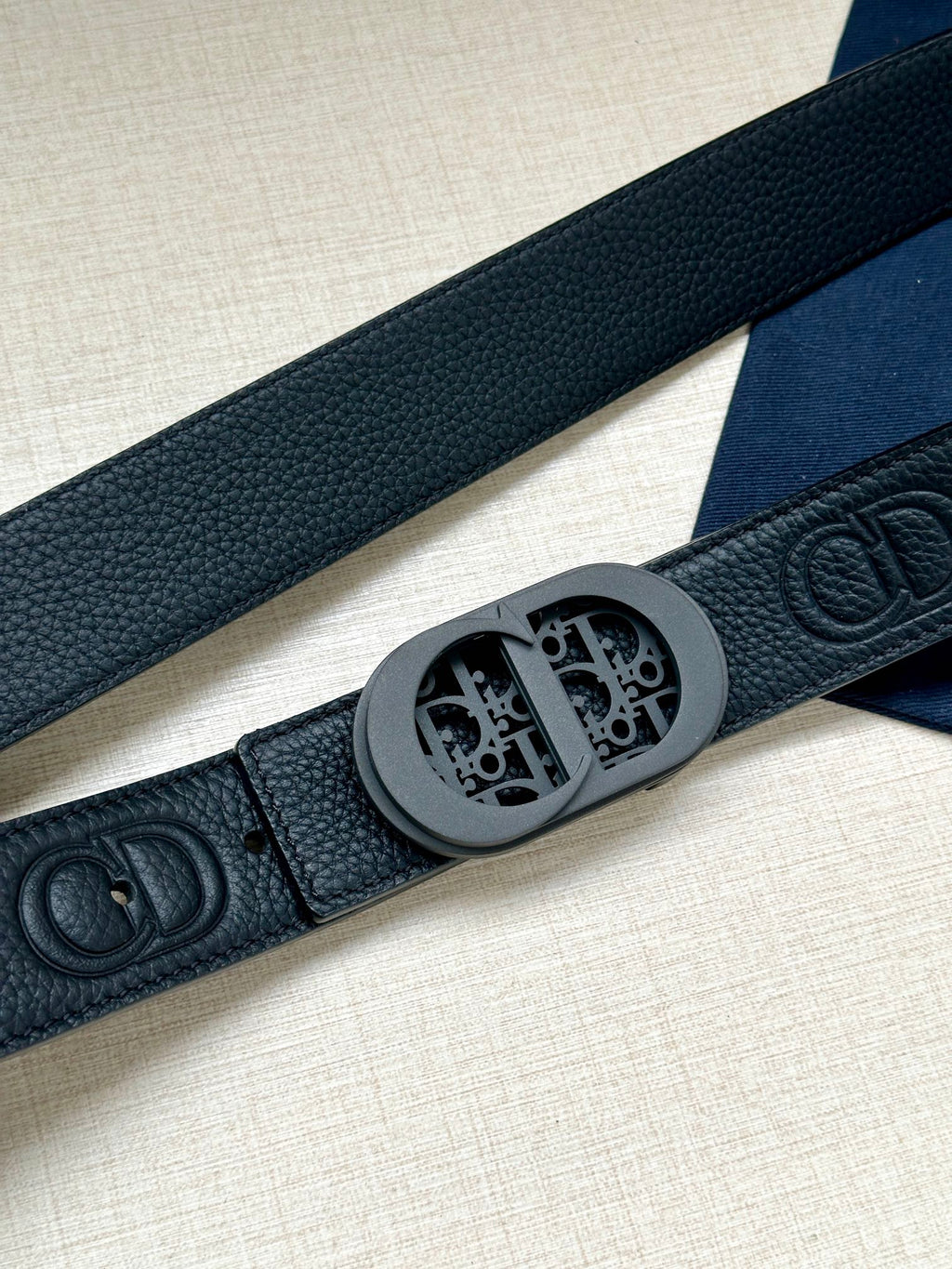Dior belt strap detail with embossed Dior logo and round buckle plate