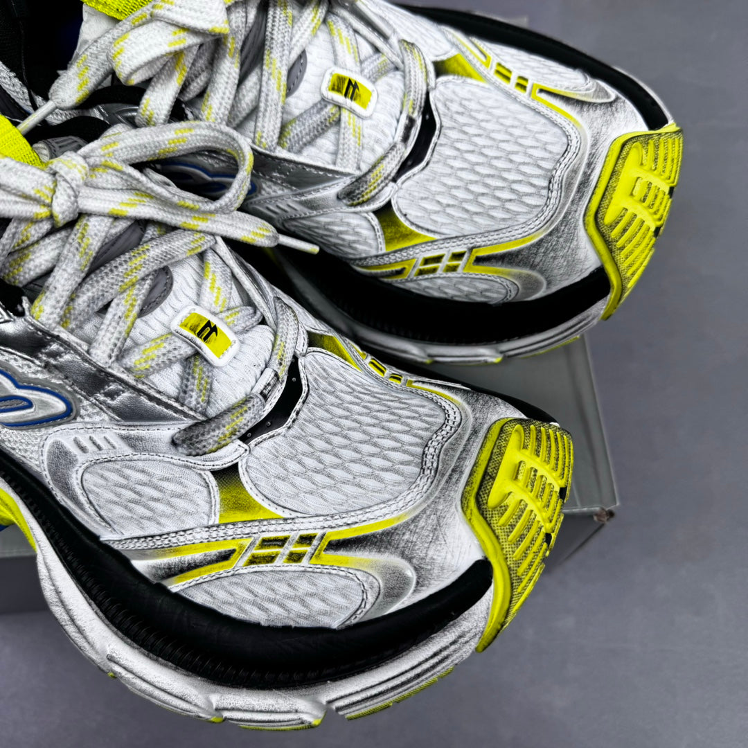 Pair of silver sneakers with textured panels, neon yellow edges, and blue accents