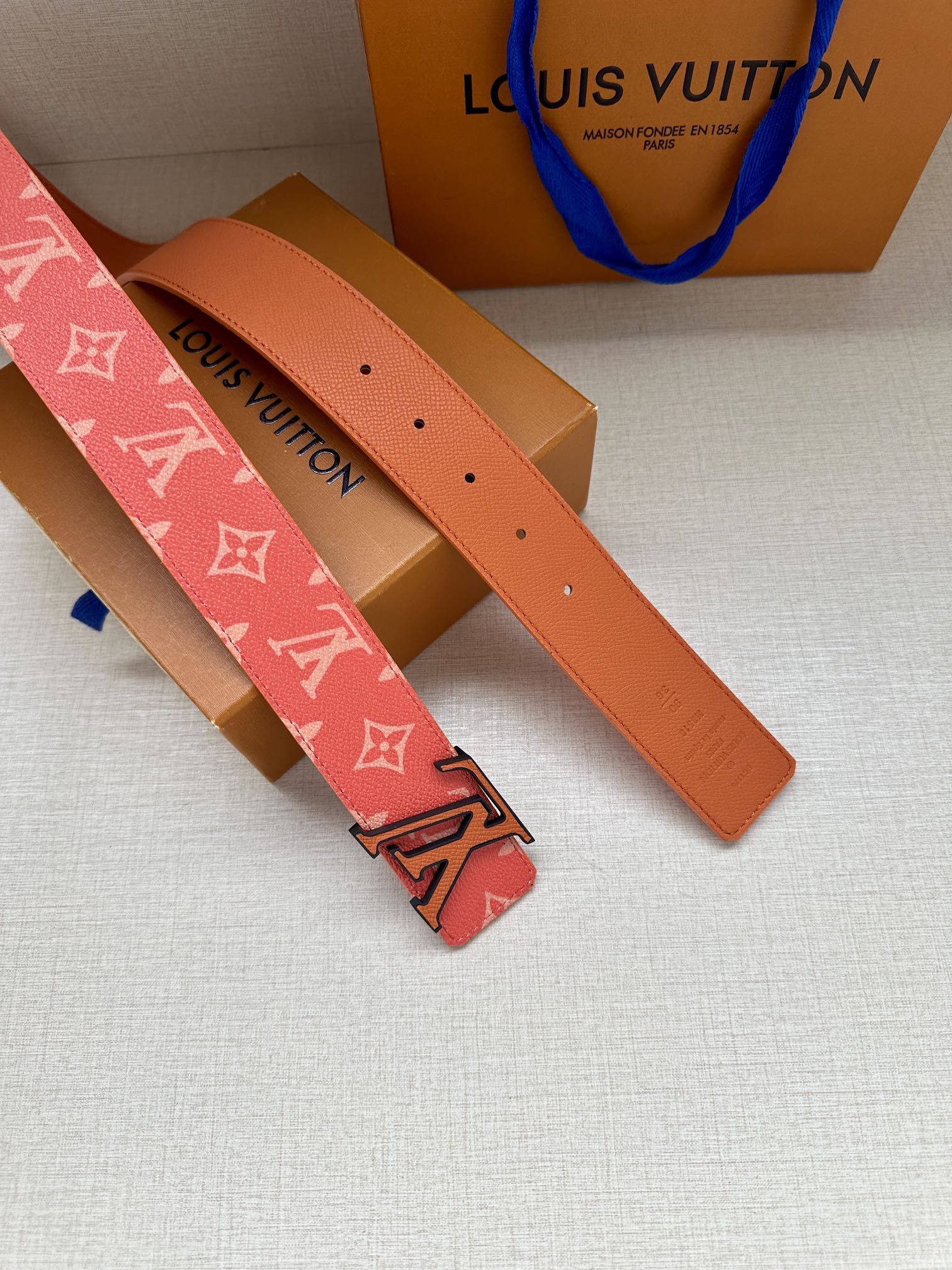 Louis Vuitton belt strap with red monogram pattern, orange leather underside and holes