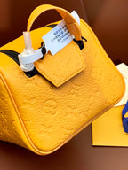 Mustard-yellow leather mini top-handle bag with attached product tag