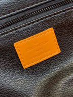 Tan label patch on dark leather bag exterior with embossed text