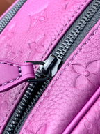 Purple embossed crossbody bag close-up with black zipper pull and stitched trim