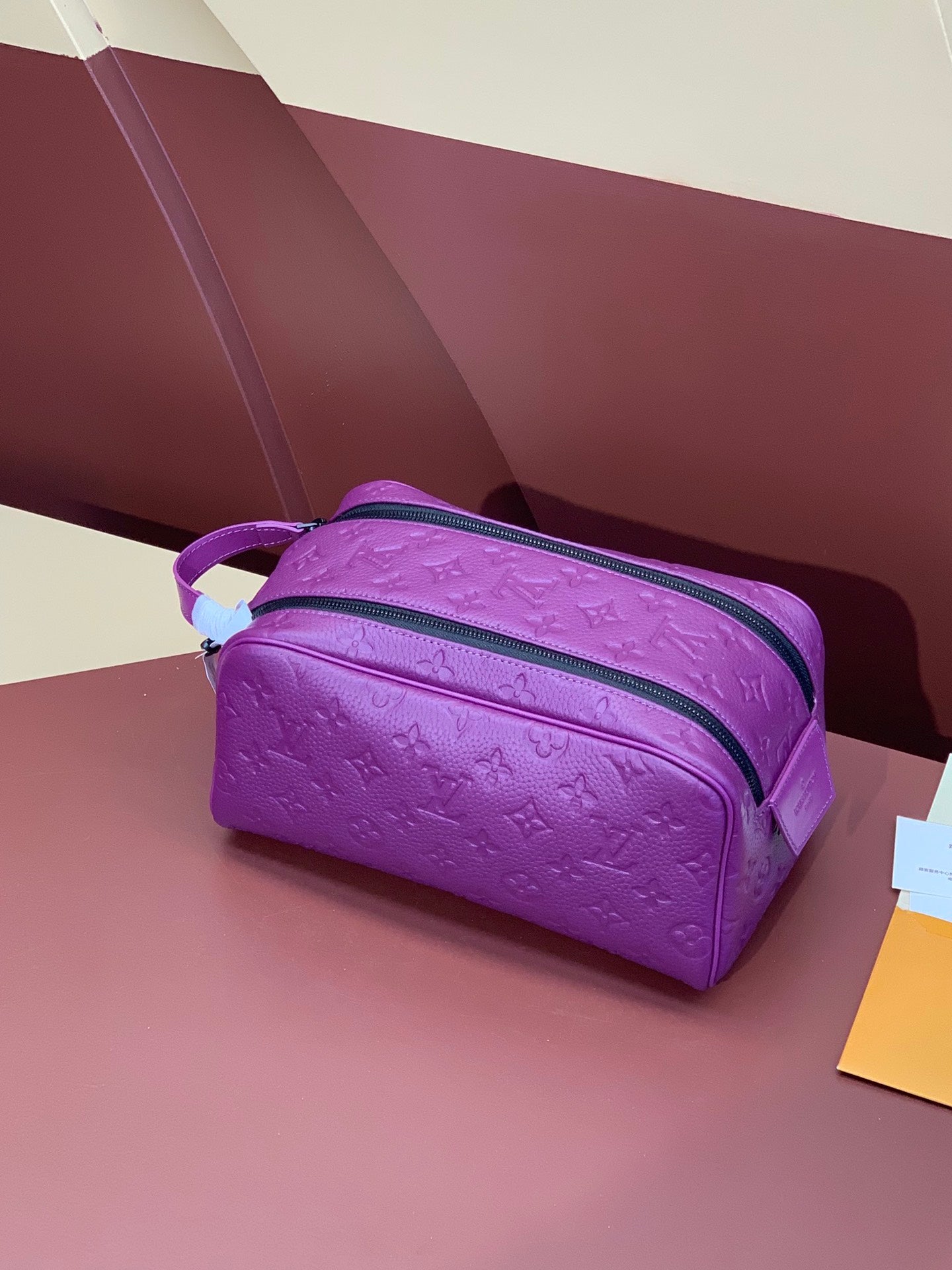 Purple embossed crossbody bag with top zip closure and adjustable shoulder strap