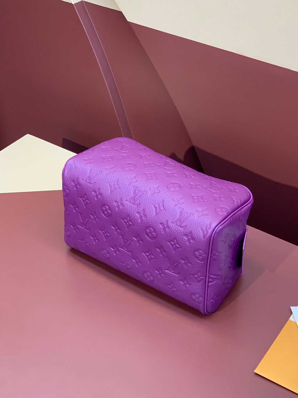 Purple embossed mini crossbody bag with rounded shape and top zipper