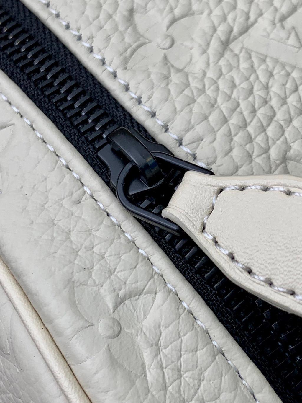 Louis Vuitton zipper close-up on white monogram pouch with black hardware